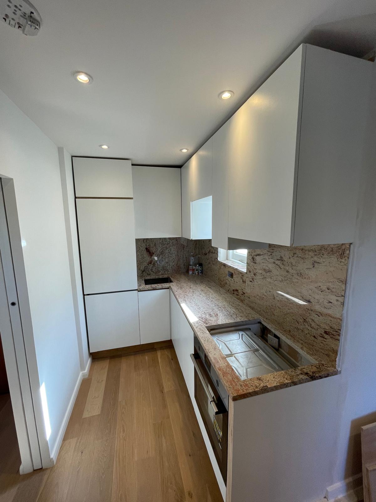 Compact white kitchen with stone surfaces and integrated appliances